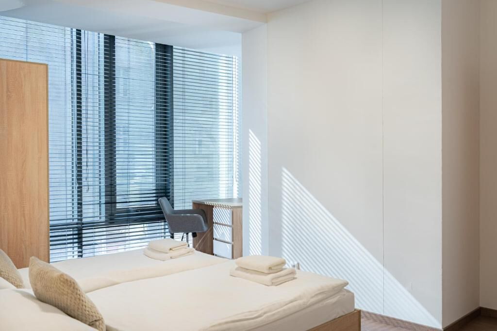 A hotel room with a bed, a desk, and a chair.