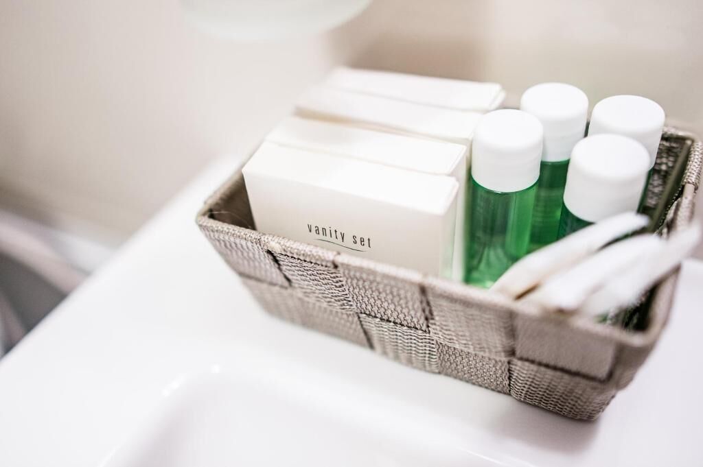 A wicker basket containing a vanity set and green bottles.