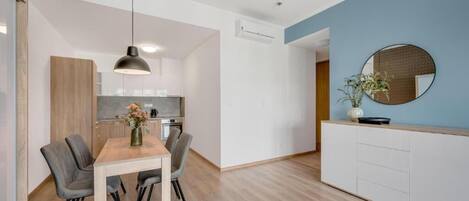 A modern kitchen with white cabinets, a wooden dining table, and a hanging pendant light.