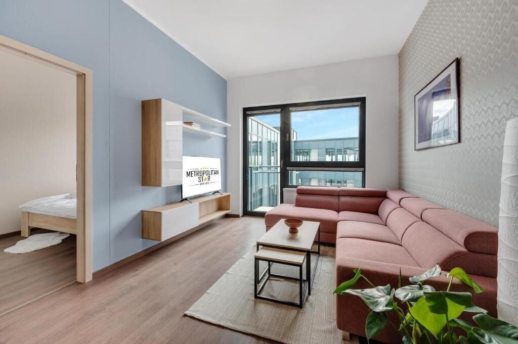 A modern living room with a sofa, a coffee table, a TV, and a large window.