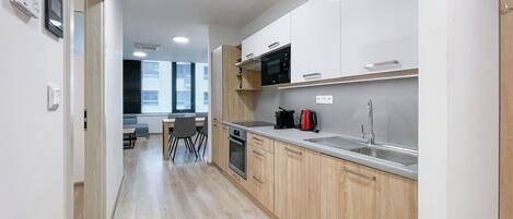 Une cuisine moderne avec des meubles en bois, un évier en acier inoxydable et un four à micro-ondes.