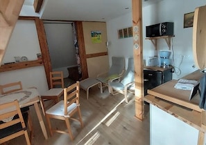 A cozy room with wooden furniture, a dining table, and a kitchenette area with a microwave and coffee maker.