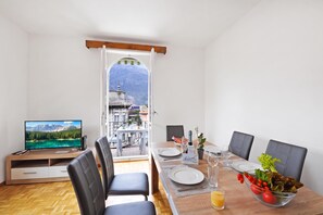 A dining area with a table set for two, a television, and a view of a mountain landscape through an open door. - Bellinzona Center (Bellinzona)