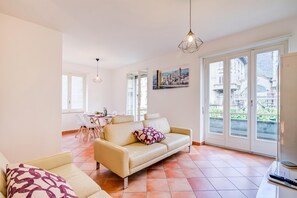 Ein Wohnzimmer mit einer Couch, einem Esstisch mit Stühlen und einem Gemälde an der Wand.