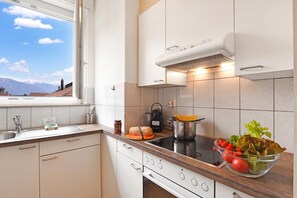 A modern kitchen with a window, a stove, and a bowl of vegetables. - Bellinzona Center (Bellinzona)