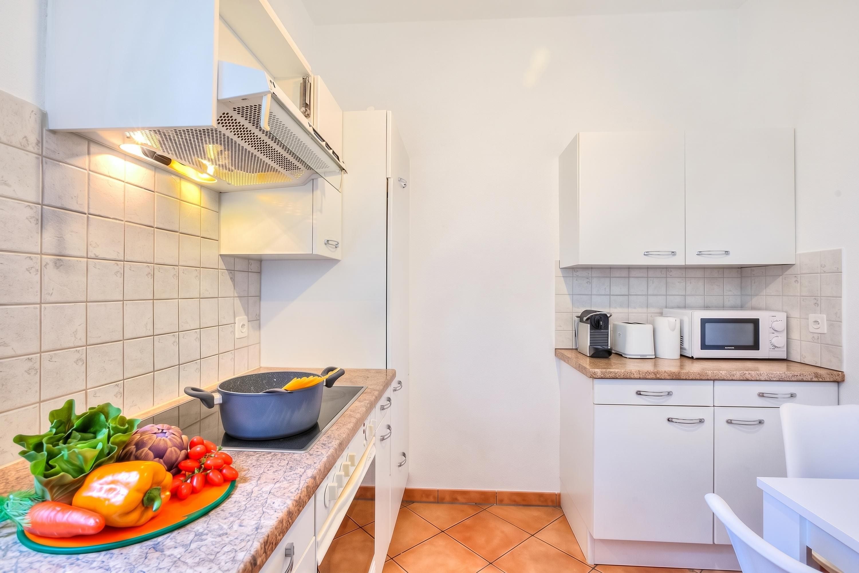 Una cucina moderna con mobili bianchi, un forno a microonde e un fornello.