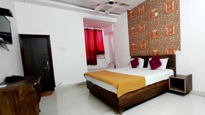 A bedroom with a wooden bed, a desk, a wardrobe, and a patterned wall. - Hotel Santosh (Jodhpur)