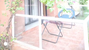 Une pièce dotée d’une porte vitrée donnant sur un balcon, d’une petite table et d’une chaise.