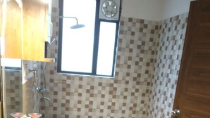 Une salle de bain avec une douche, un lavabo et une fenêtre.