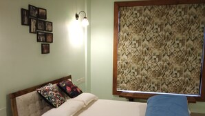 Une chambre à coucher avec un lit, un climatiseur fixé au mur, des tableaux encadrés et un store à motifs.