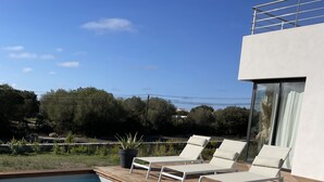 Ein Schwimmbecken mit Liegestühlen und ein modernes Gebäude mit großen Fenstern.