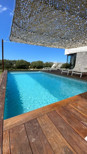 A swimming pool with a wooden deck and a white fence.