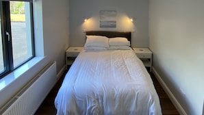 Un dormitorio con una cama grande, una ventana, un radiador y una lámpara en el techo.