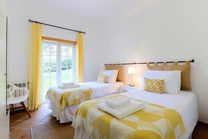 A hotel room with two beds, a chair, and a window with curtains.