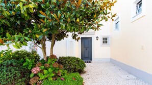 A cobblestone pathway leading to a building with a dark door and a small window.