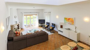 A spacious living room with a sofa, TV, and seating area.
