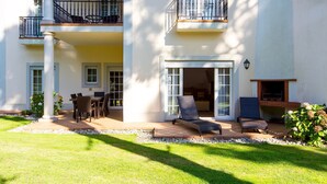 A two-story building with a patio area featuring outdoor furniture, a dining table, and a fireplace.