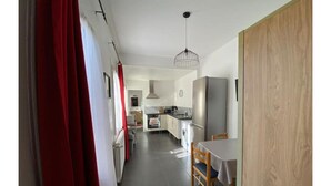Eine moderne Küche mit Essbereich, einem roten Vorhang und einer Holztür.