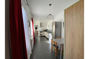 Una cocina moderna con comedor, una cortina roja y una puerta de madera.
