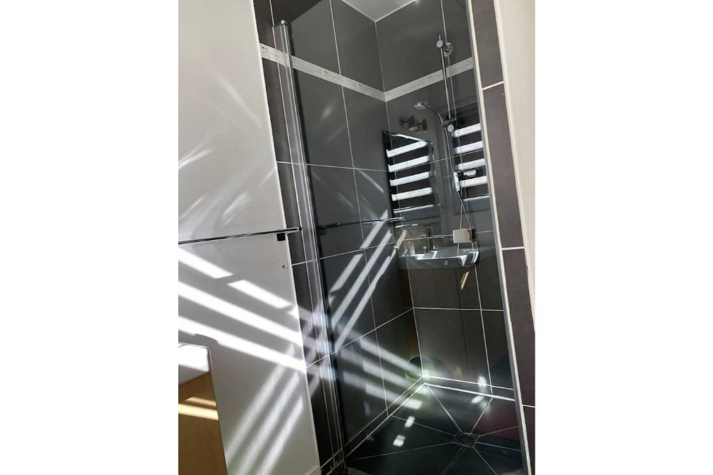 A modern shower with a glass enclosure and a rain showerhead.