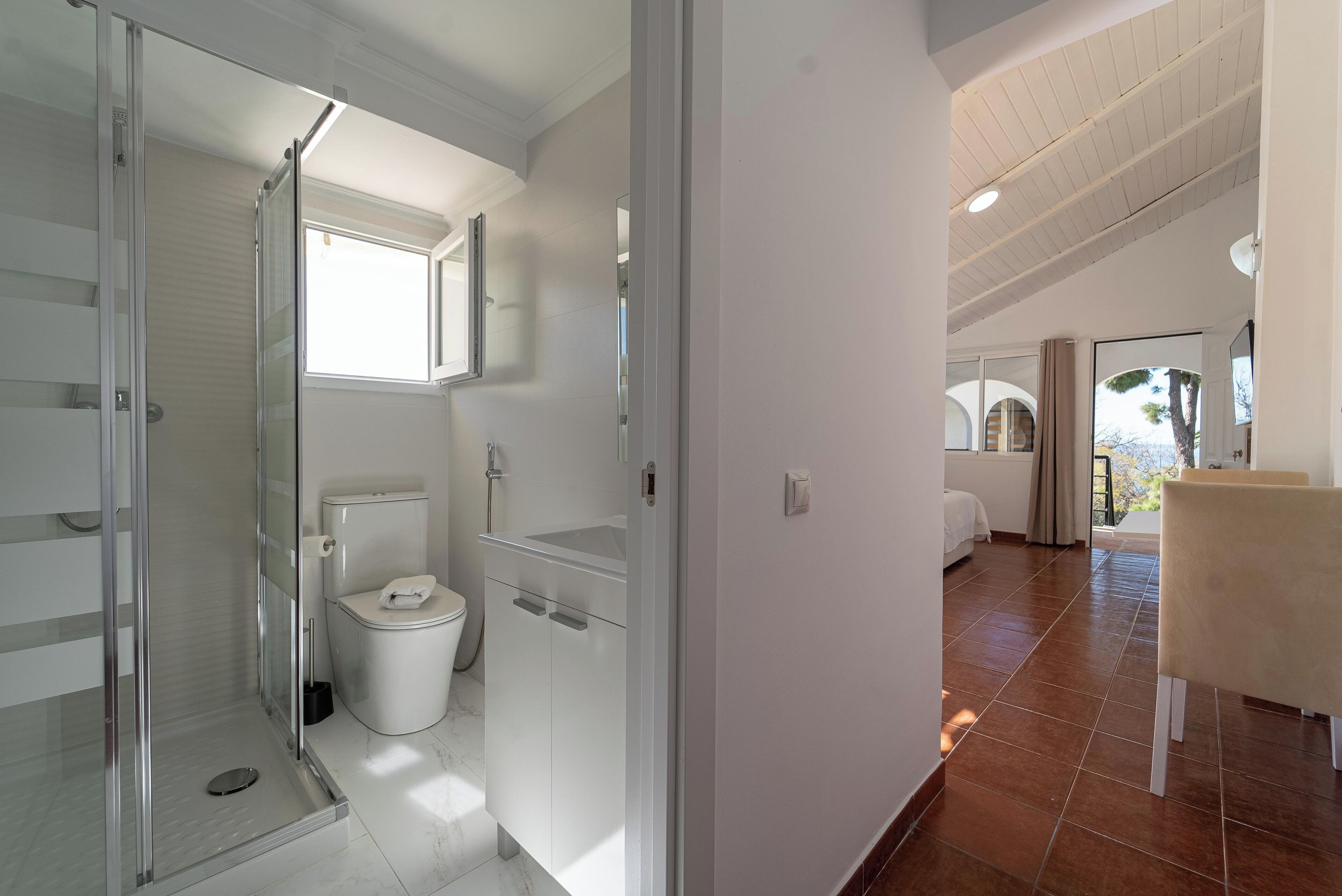 A modern bathroom with a glass shower enclosure, a toilet, and a sink.
