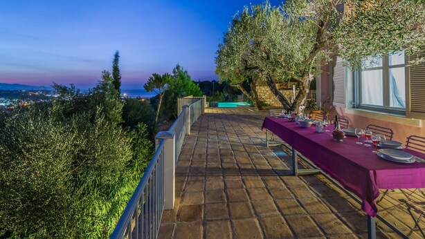Eine Terrasse mit Esstisch, mit Blick auf eine schöne Landschaft aus Meer und Hügeln.