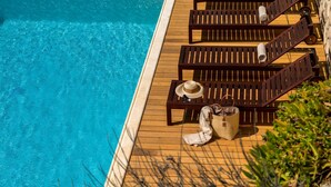 Eine Holzterrasse mit Liegestühlen und einem Pool.