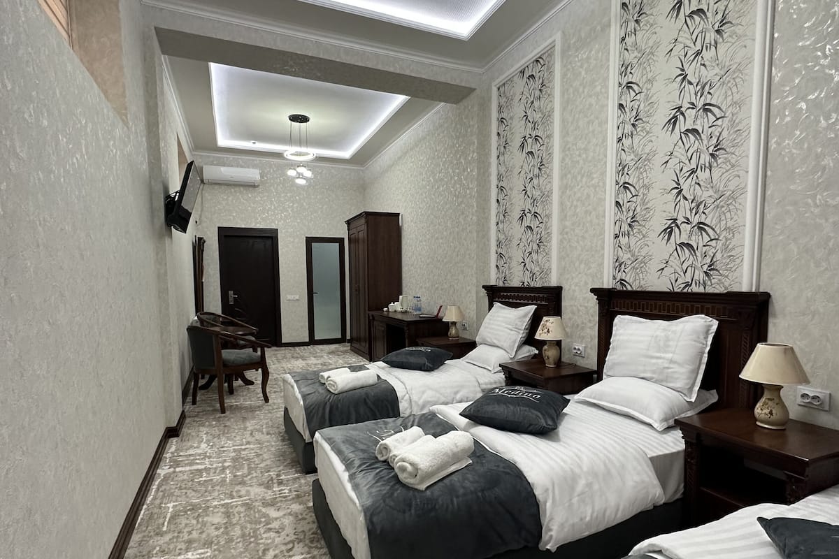 A hotel room with three beds, a desk, and a chair.