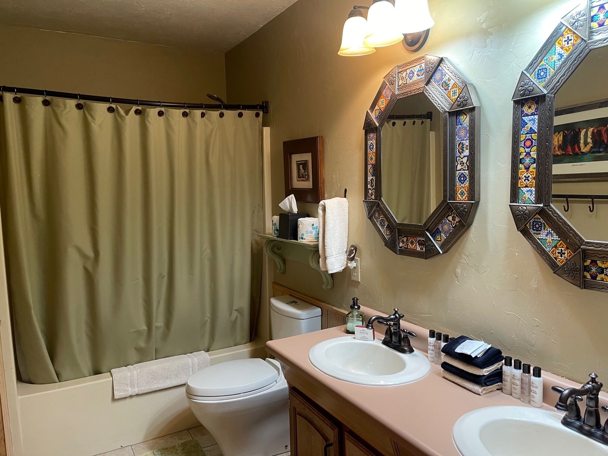 A bathroom with a bathtub, two sinks, a toilet, and decorative mirrors.