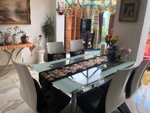 A dining area with a glass table, black upholstered chairs, and a decorative runner.