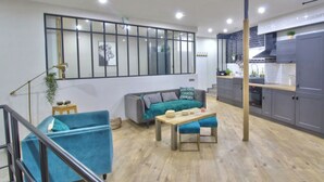 Un salon moderne comprenant un canapé, une table basse et une table à manger. Il y a également un coin cuisine avec des placards et un plan de travail.