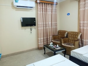 Relax in a serene space with a flat-screen TV, comfortable chairs, and a cozy bed.