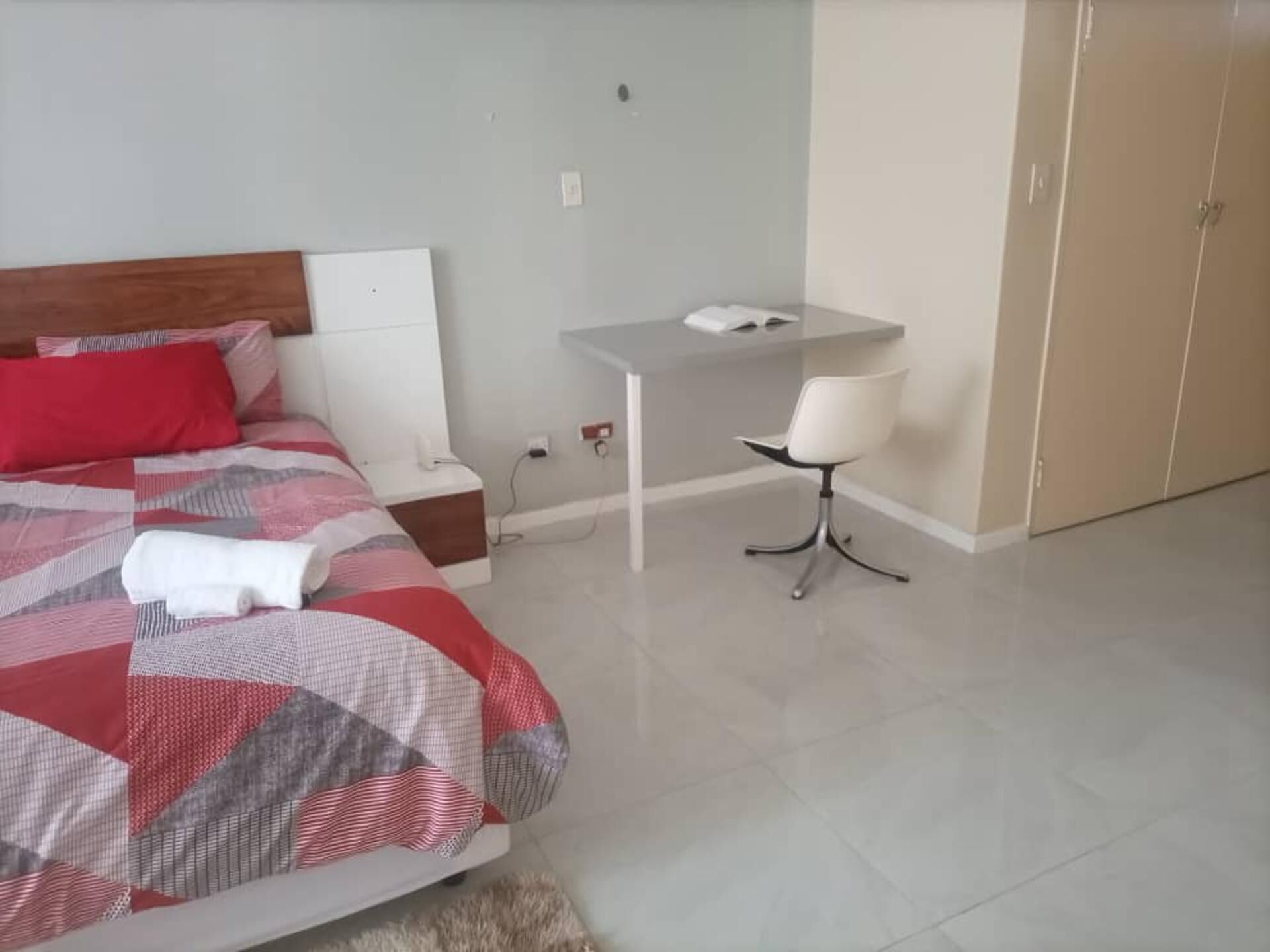 Een slaapkamer met een bed, bureau, stoel en garderobe.