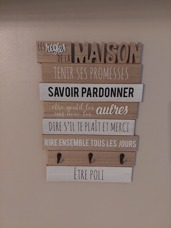 Een muur met houten plaquettes waarop Franse zinnen staan.