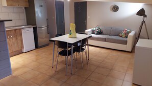 A compact living space with a kitchenette, a dining area, and a seating area. - Small cottage in the countryside, near the sea (Lampaul-Ploudalmézeau)