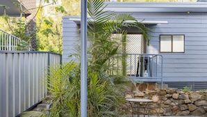 A modern house with a stone wall, a metal gate, and a small patio with a table and chairs. - Studio 21 - walk to beach marina cafes (Nelson Bay)