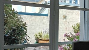 Habitación con un ventanal grande que da a un patio con plantas y barandilla azul.