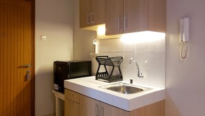 Une cuisine compacte avec des meubles en bois, un évier encastré, une machine à café et un petit réfrigérateur.