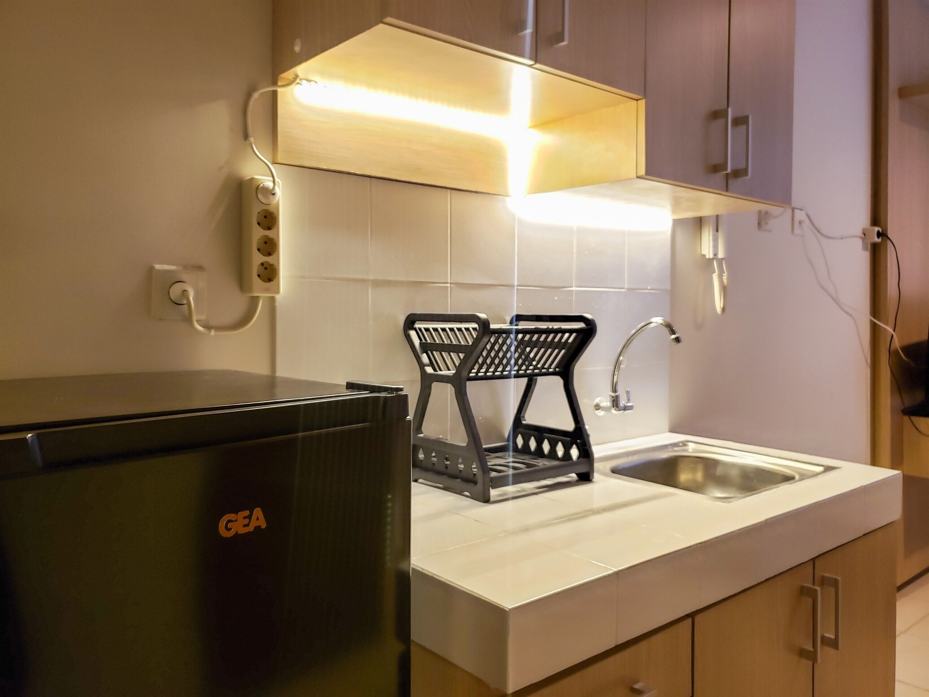 A compact kitchen with a built-in GE refrigerator, a sink, and a black chair with a mesh backrest.
