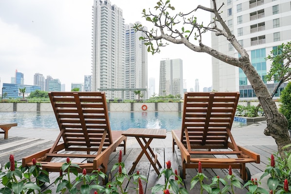 Relax by the pool surrounded by lush greenery and flowering plants.