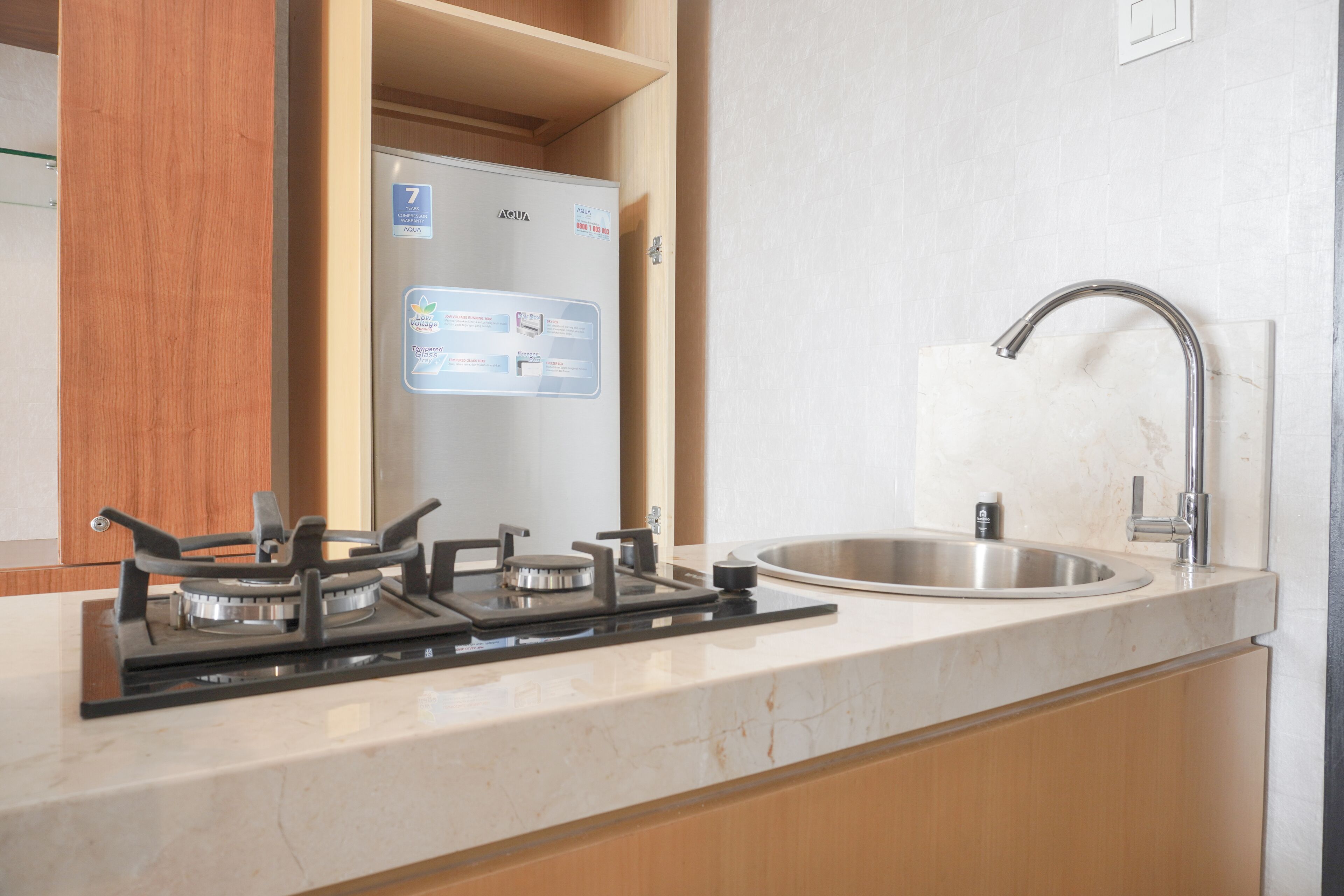 Una cocina con estufa a gas, un lavamanos de acero inoxidable y armarios de madera.