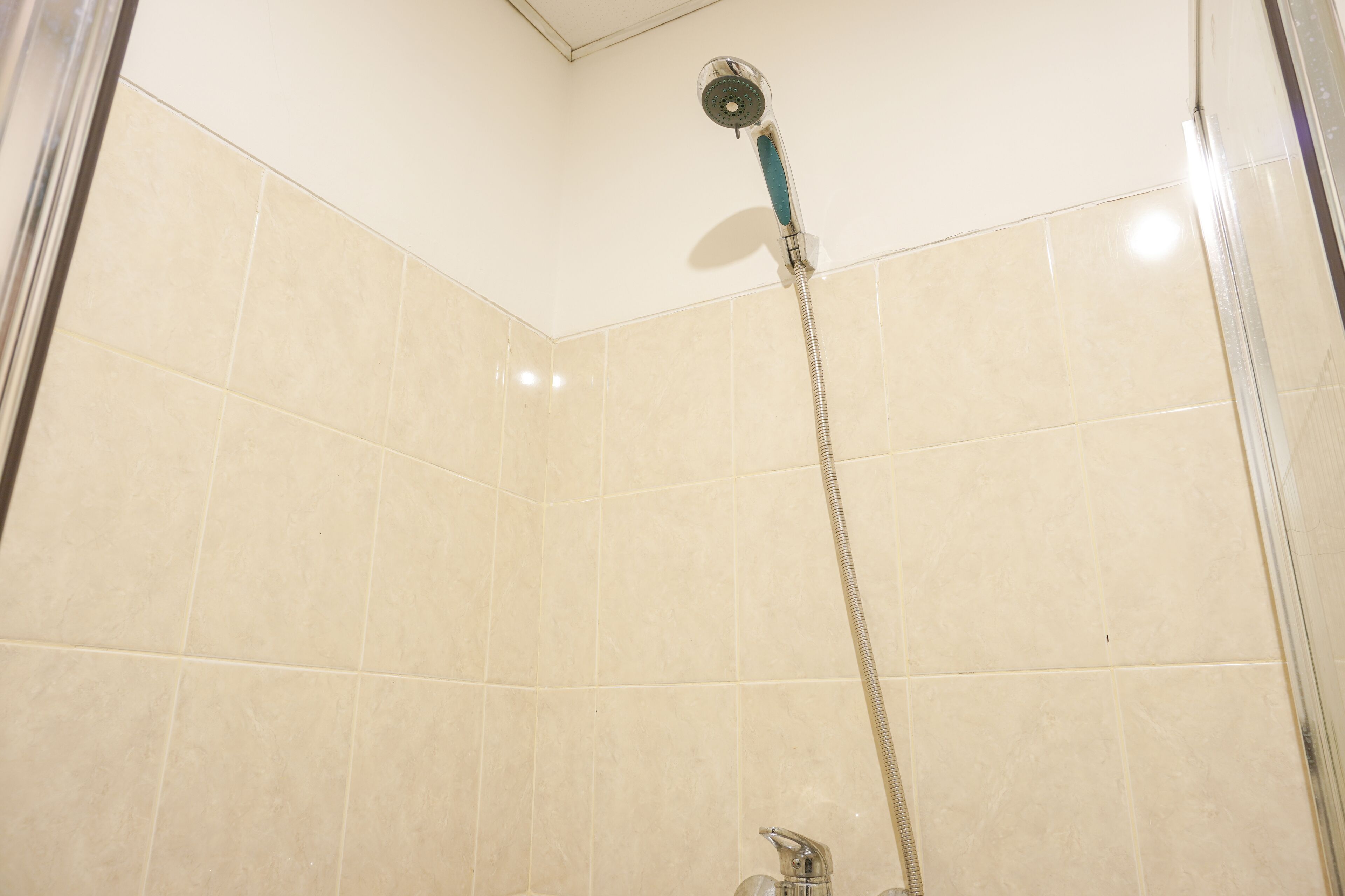 A shower with a handheld showerhead and a wall-mounted faucet.