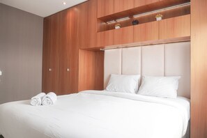 Relax in comfort with a large bed and shelf, featuring a padded headboard and white bedding.