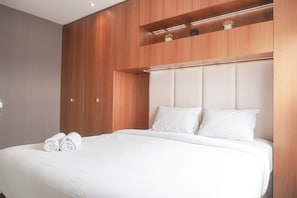Relax in comfort with a large bed and shelf, featuring a padded headboard and white bedding.