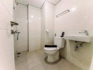 A small, modern bathroom with a toilet, a shower, and a sink. - Cozy Studio Room At Barsa City Apartment (Depok)