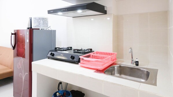 Una cocina con estufa a gas, un lavamanos y un refrigerador.