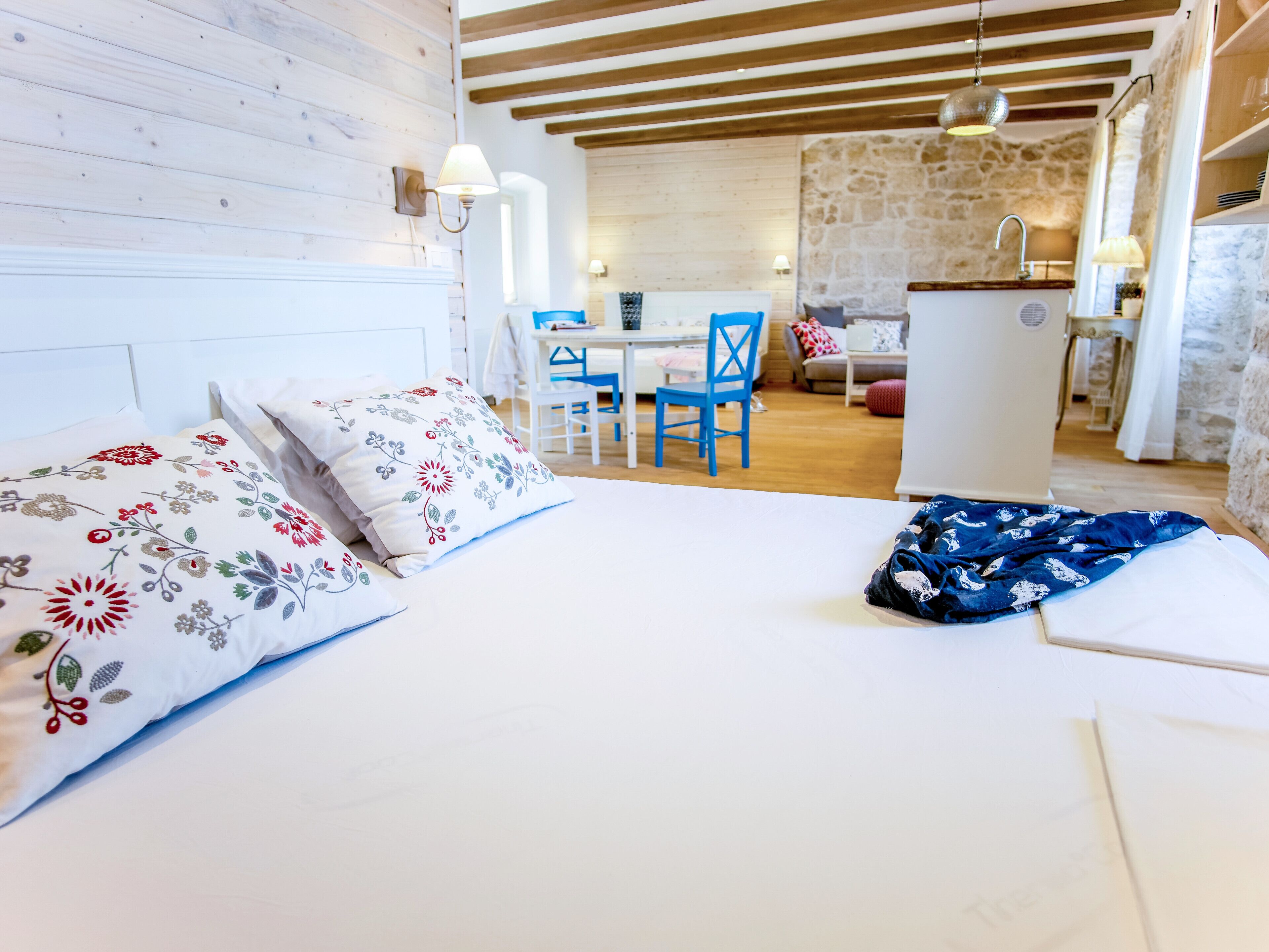 A bedroom with a bed, a desk, and a kitchenette.