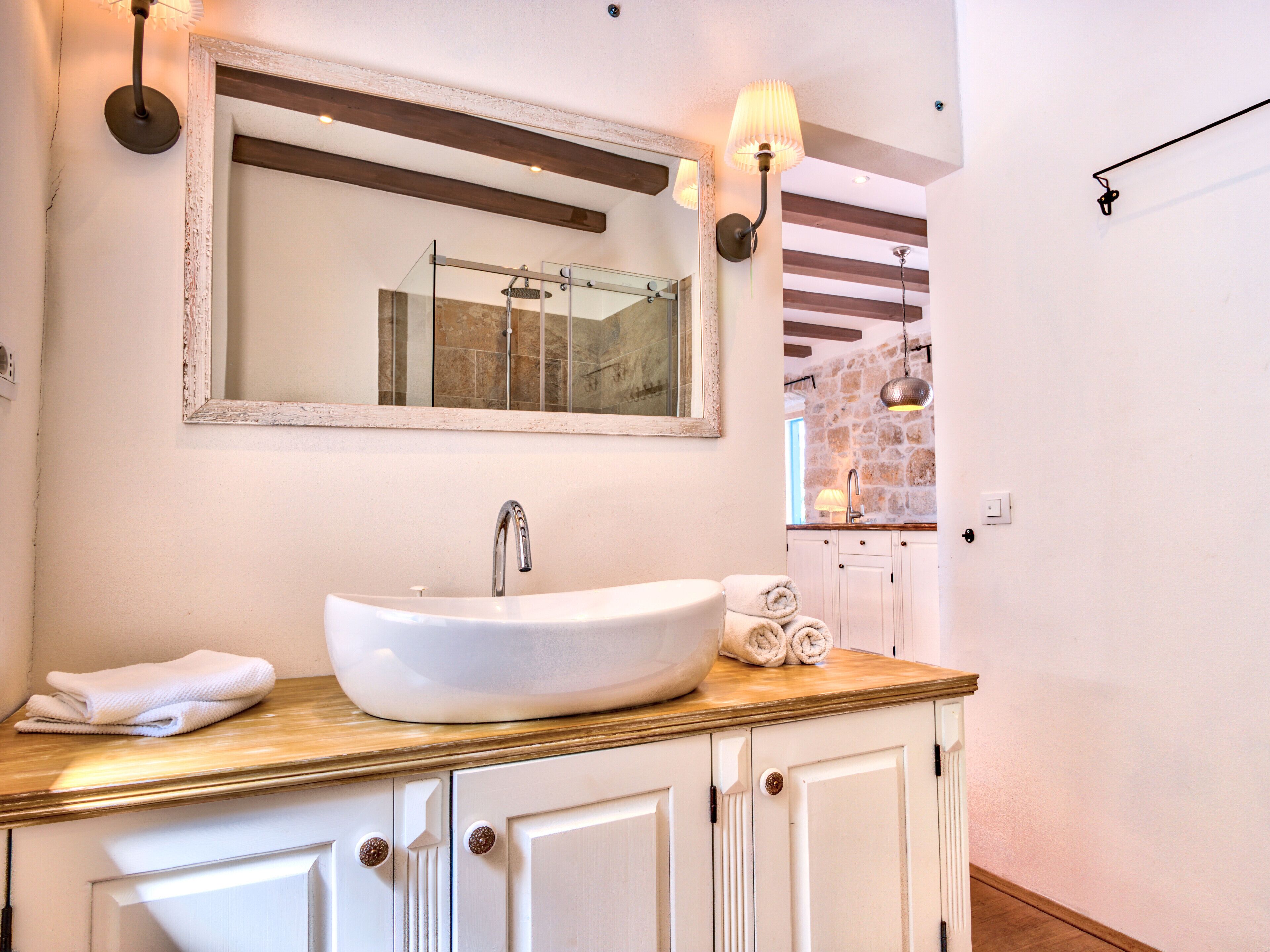A bathroom with a large white sink, a mirror above it, and a towel on the counter.