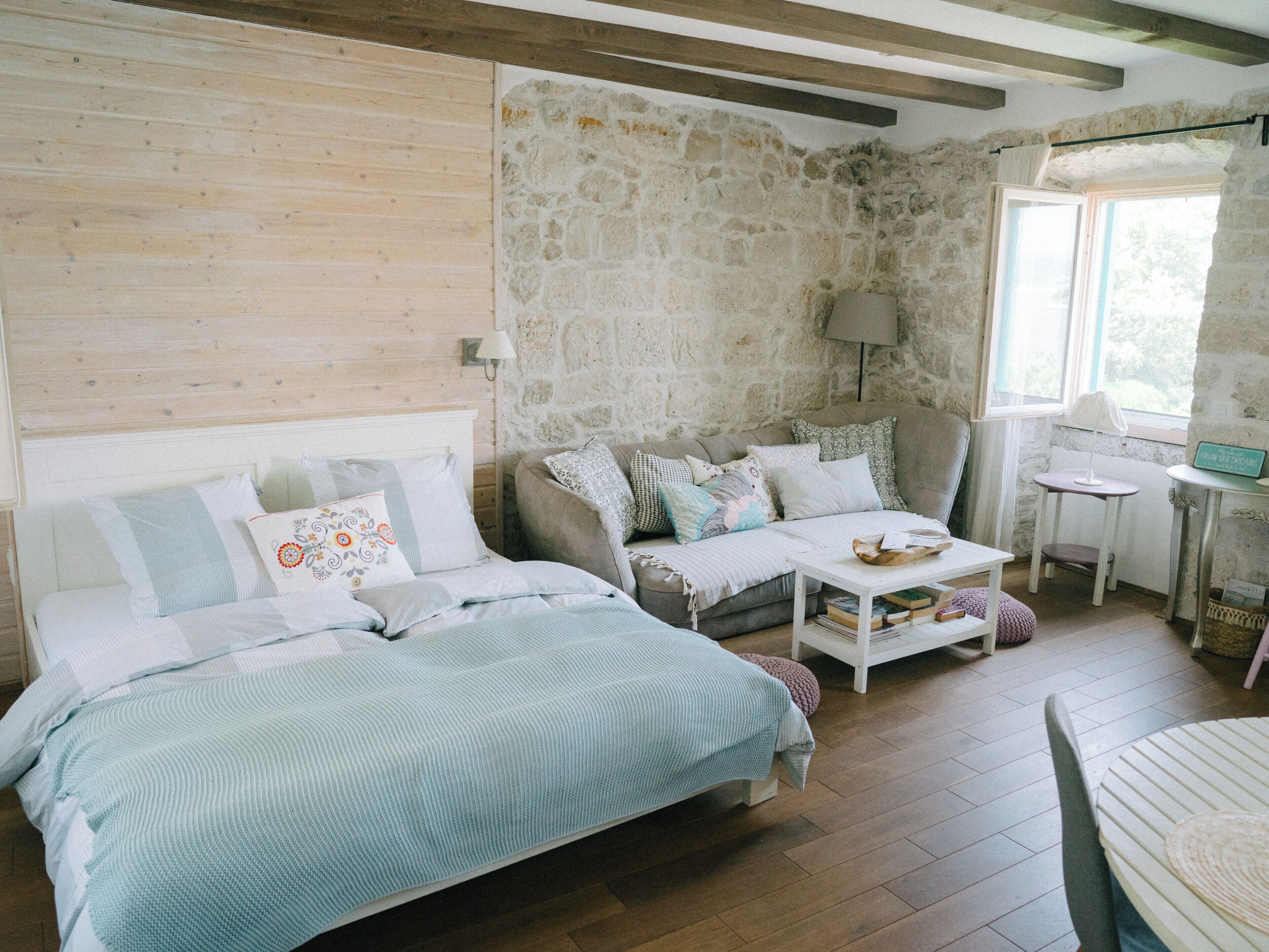 A cozy bedroom with a bed, a sofa, a small table, and a chair.