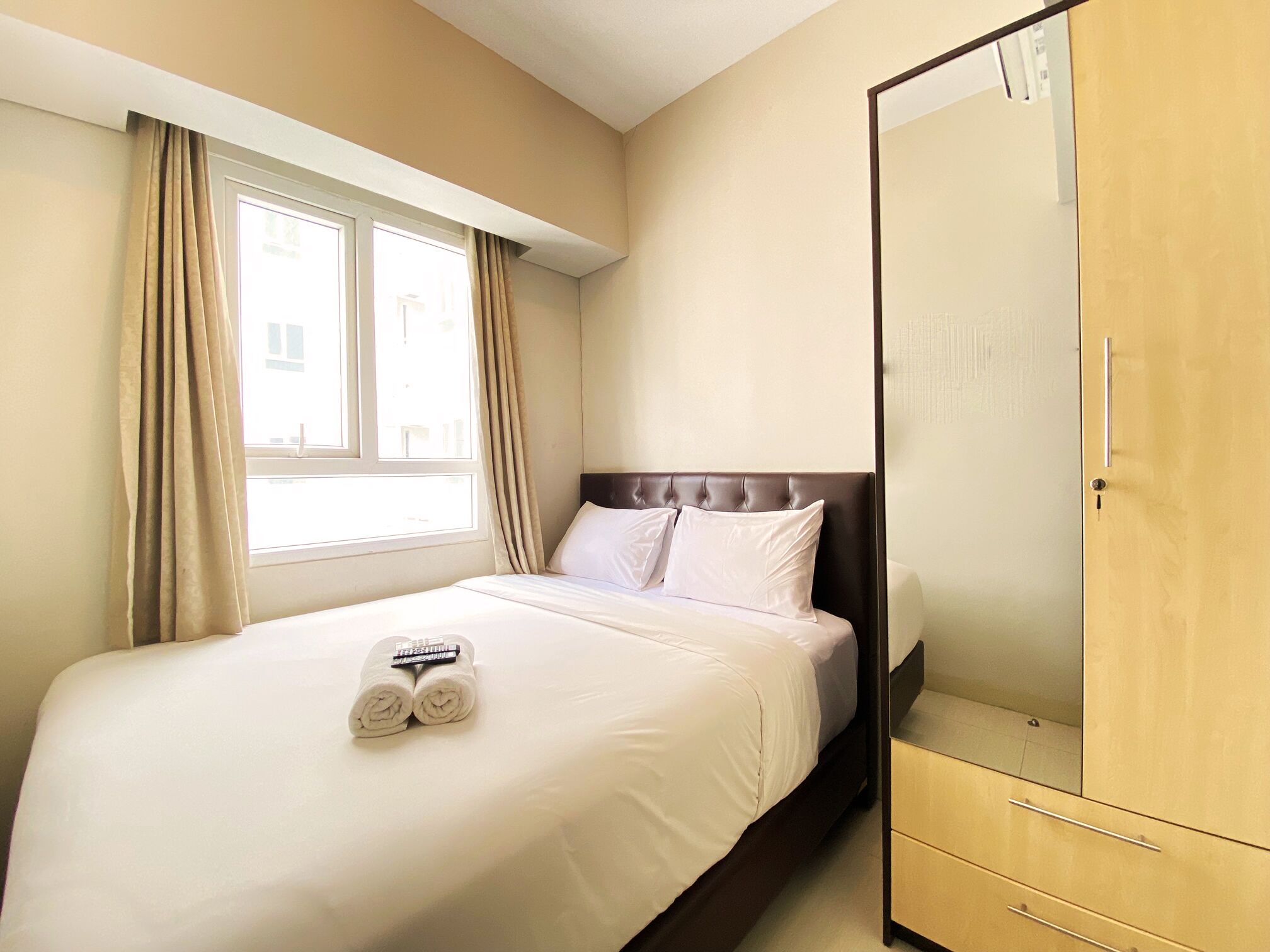 Une chambre d’hôtel avec un lit, une armoire et une fenêtre avec des rideaux.